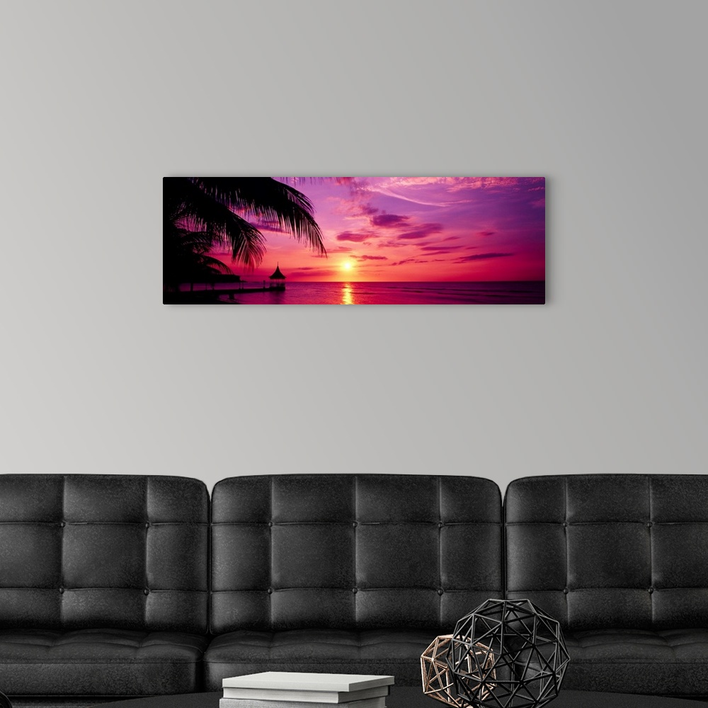 A modern room featuring Panoramic photograph of a colorful sunset on the beach in Montego Bay, Jamaica.  The palm trees a...