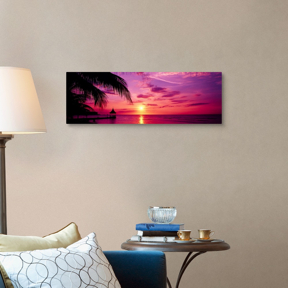 A traditional room featuring Panoramic photograph of a colorful sunset on the beach in Montego Bay, Jamaica.  The palm trees a...