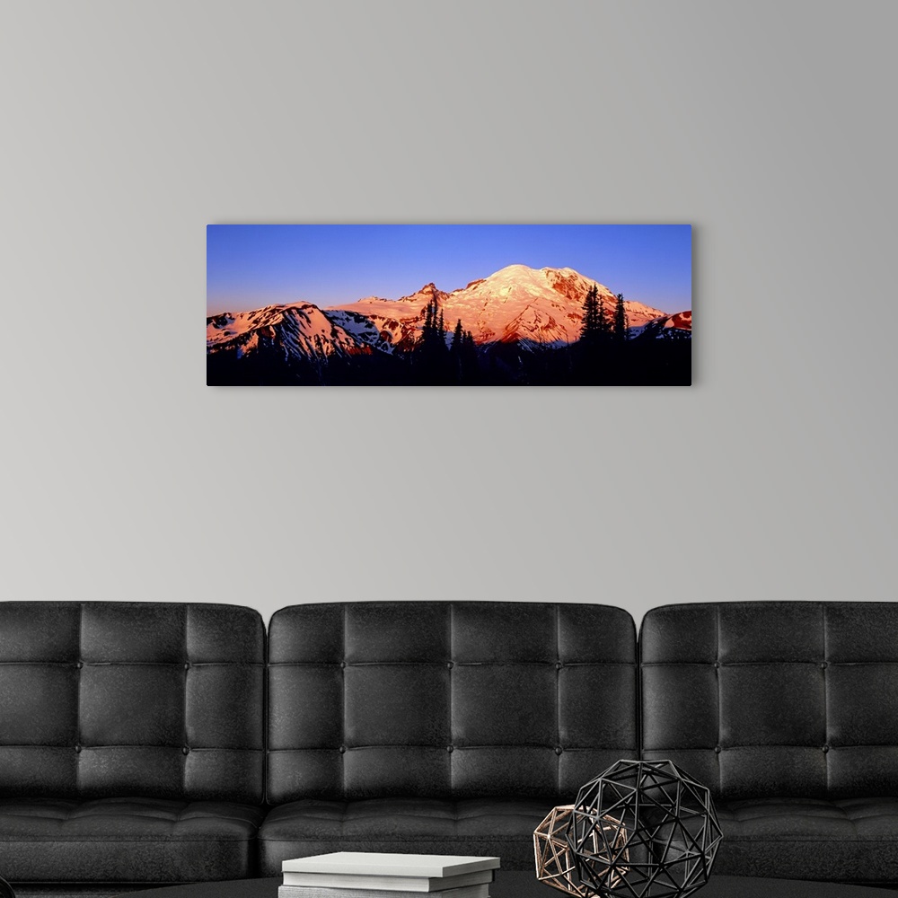 A modern room featuring Panoramic photograph taken of snow topped mountains during sunset with the trees in front silhoue...