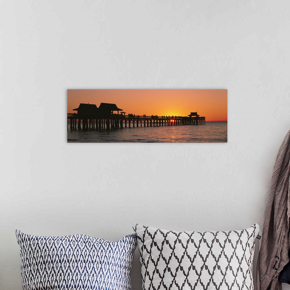 A bohemian room featuring Panoramic canvas photo art of a silhouetted pier at sunset on the ocean.