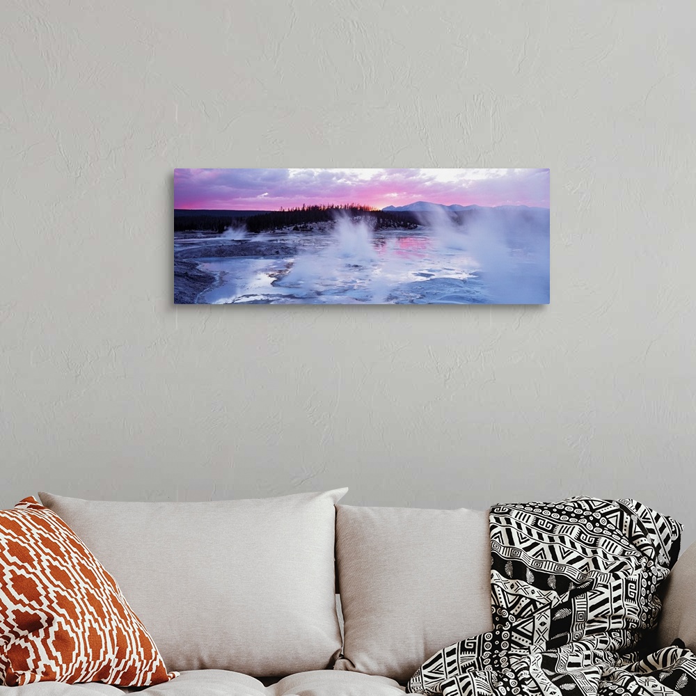 A bohemian room featuring Large panoramic piece of geysers in Wyoming as the sun sets in the distance and gives the sky pin...
