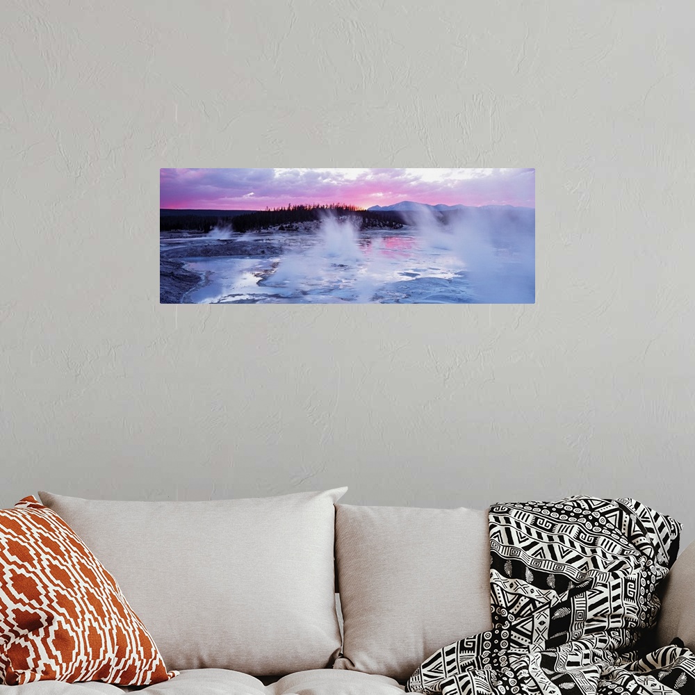 A bohemian room featuring Large panoramic piece of geysers in Wyoming as the sun sets in the distance and gives the sky pin...