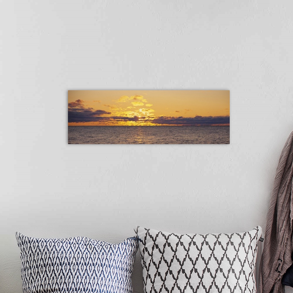 A bohemian room featuring Panoramic photo on canvas of a sunset shining through clouds above a lake.