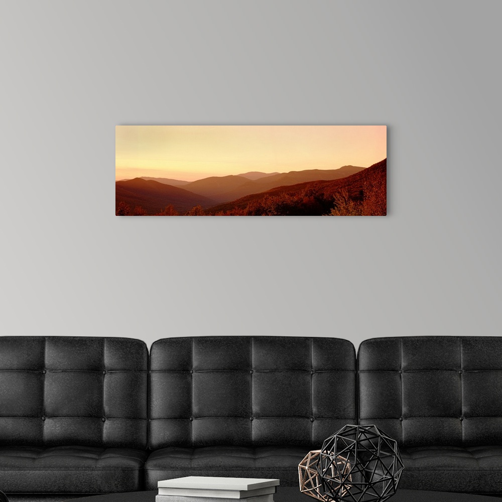 A modern room featuring Large panoramic image of rolling mountains in the foggy sunset.