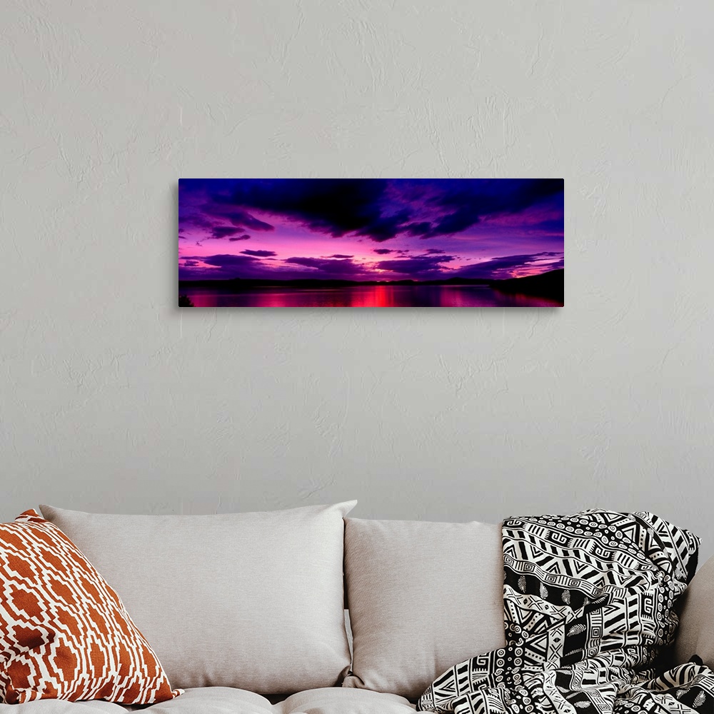 A bohemian room featuring A panoramic photograph of clouds in the sky and light reflecting off water in the twilight colors.