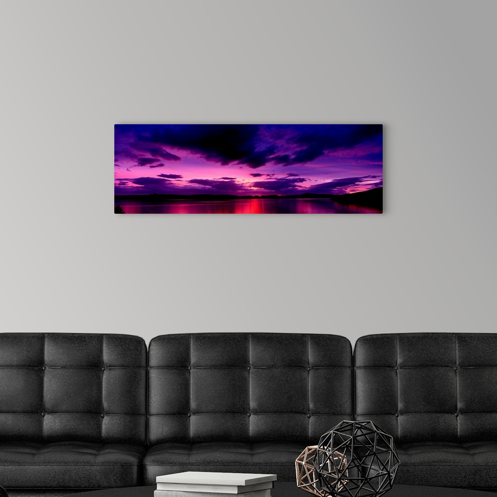 A modern room featuring A panoramic photograph of clouds in the sky and light reflecting off water in the twilight colors.
