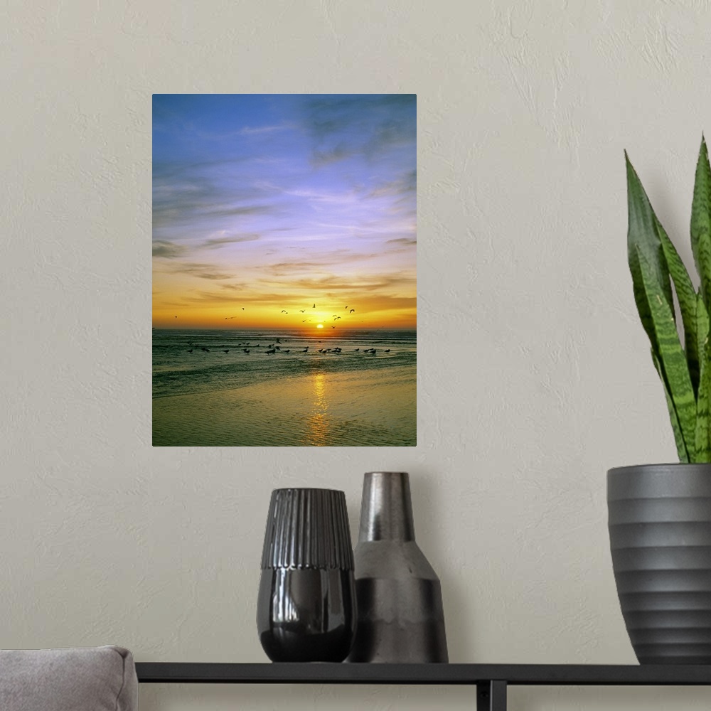 A modern room featuring Giant, vertical photograph of a vibrant sunset circled by a flock of birds, some that have landed...