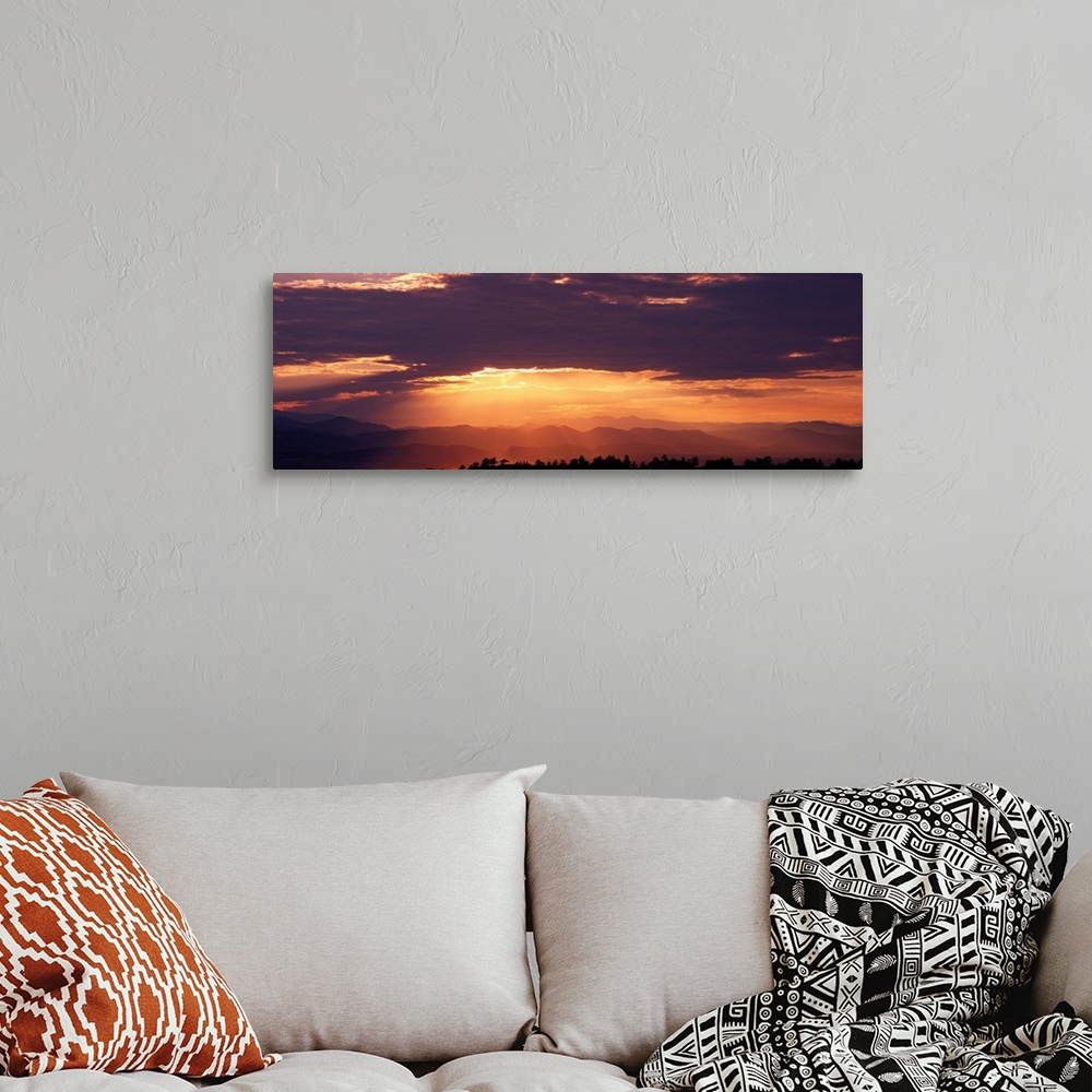 A bohemian room featuring Wide angle photograph of the sun setting behind a cloudy sky, over the distant Rocky Mountains.  ...