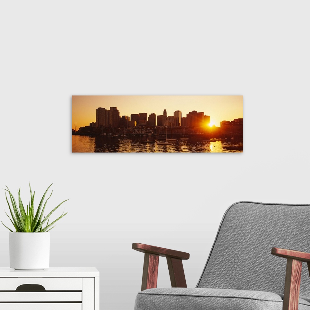 A modern room featuring The sun breaks though the skyscrapers in downtown Boston, Massachusettes (MA) as the sun sets and...