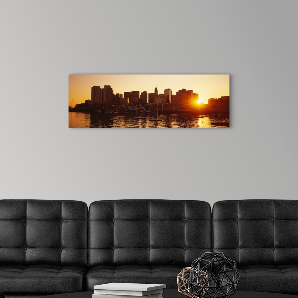 A modern room featuring The sun breaks though the skyscrapers in downtown Boston, Massachusettes (MA) as the sun sets and...