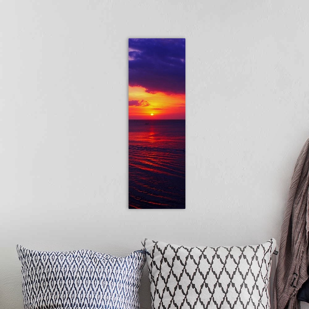 A bohemian room featuring Vertical, large photograph of the sun setting in a vibrant, fiery sky over dark ocean waters, nea...