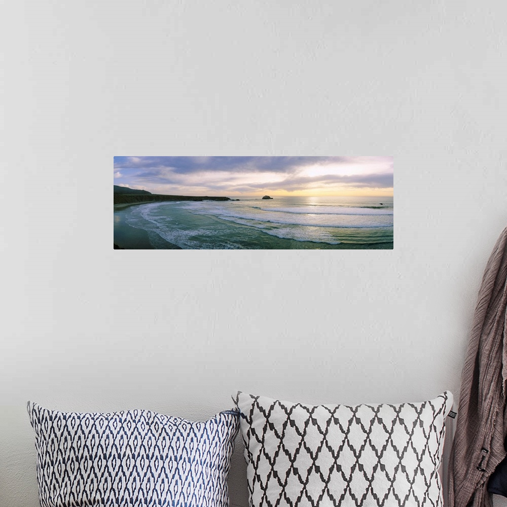 A bohemian room featuring This panoramic wall art is a wide angle photograph of waves washing on to a beach taken from a cl...