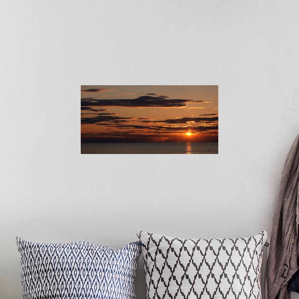 A bohemian room featuring A seascape panoramic photograph of sunlight reflecting on water and clouds on the New England coast.