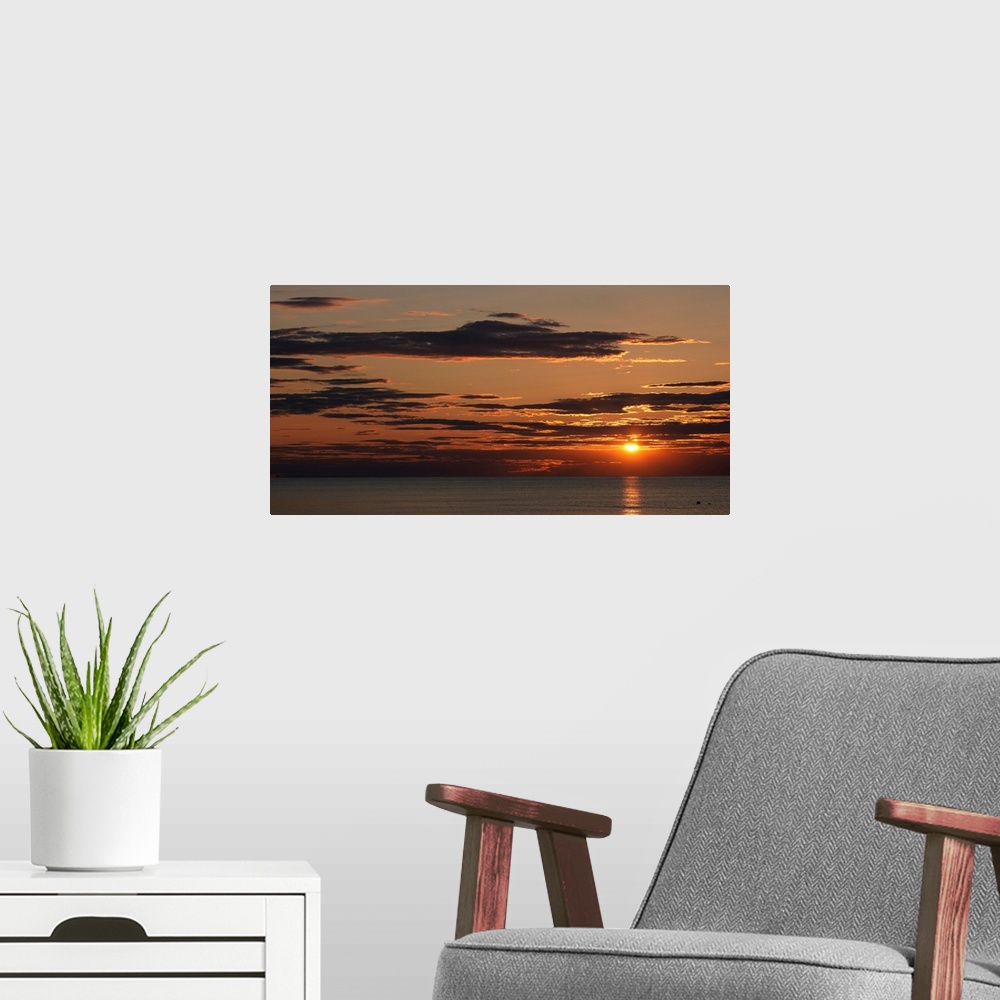 A modern room featuring A seascape panoramic photograph of sunlight reflecting on water and clouds on the New England coast.
