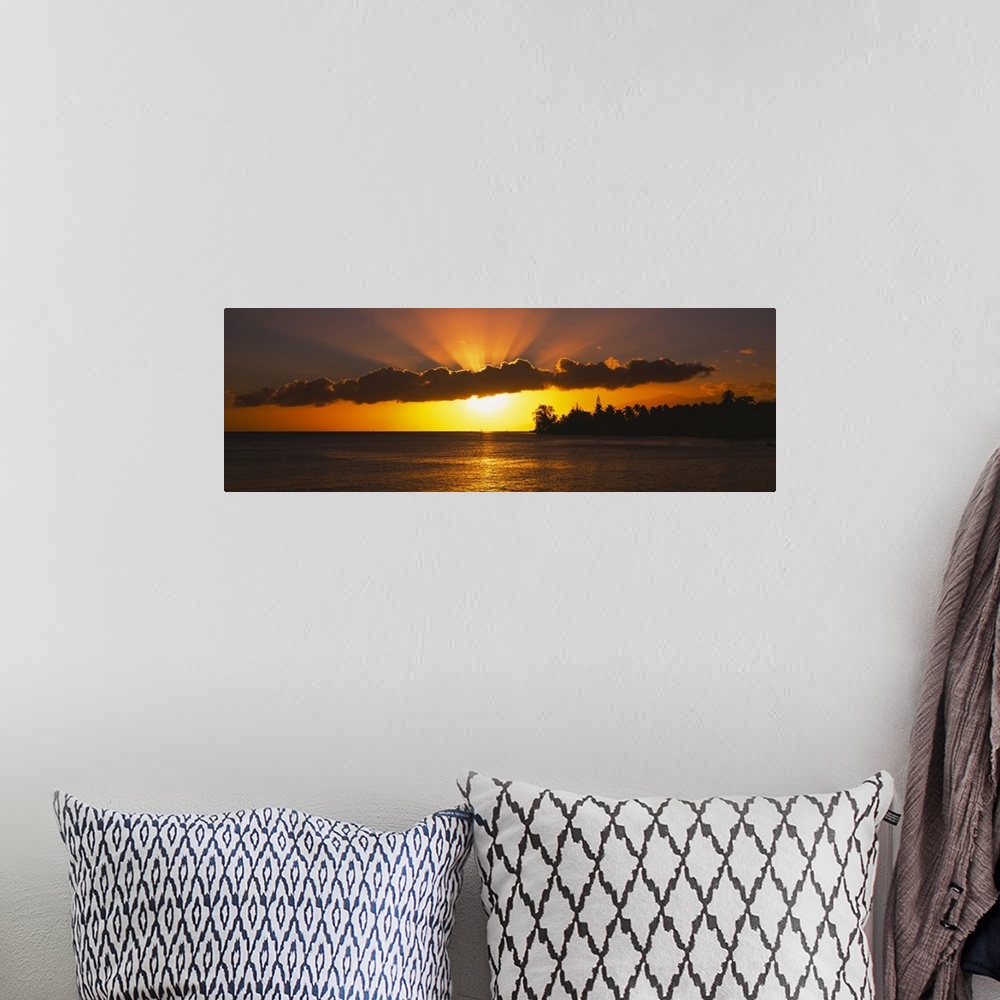 A bohemian room featuring Panoramic photograph of the sun setting behind the clouds over the water in Tahiti.