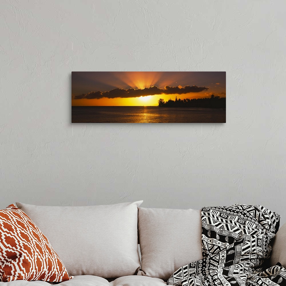 A bohemian room featuring Panoramic photograph of the sun setting behind the clouds over the water in Tahiti.