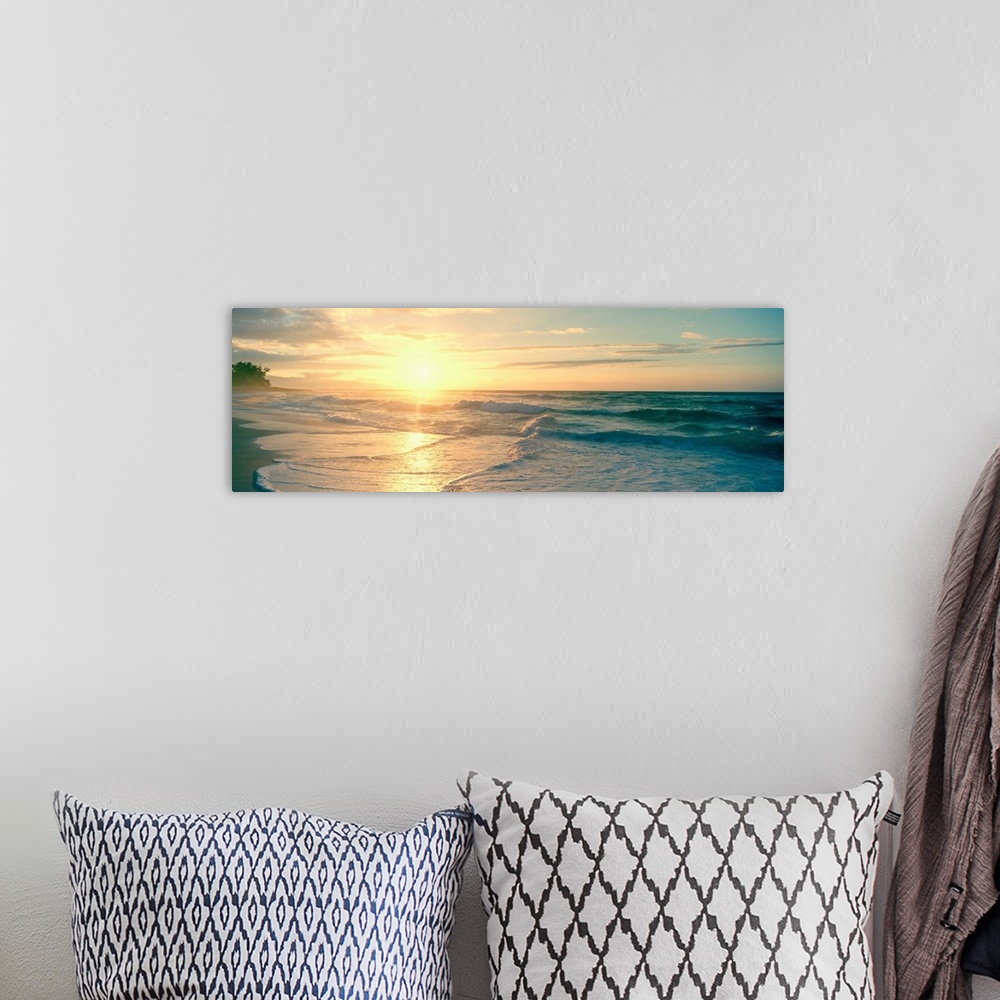 A bohemian room featuring Long panoramic print of an intense setting sun going down over the ocean with waves washing ashor...