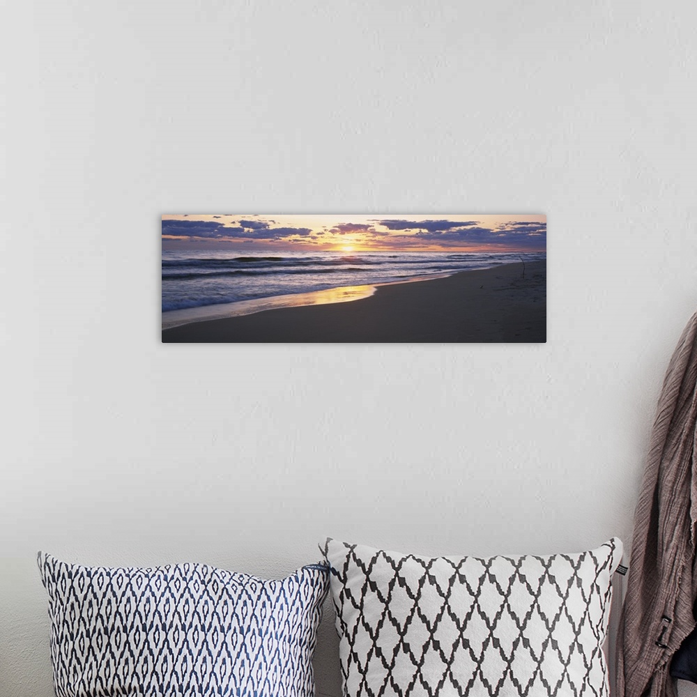 A bohemian room featuring The sand and ocean are pictured in wide angle view with the sunset off in the distance.