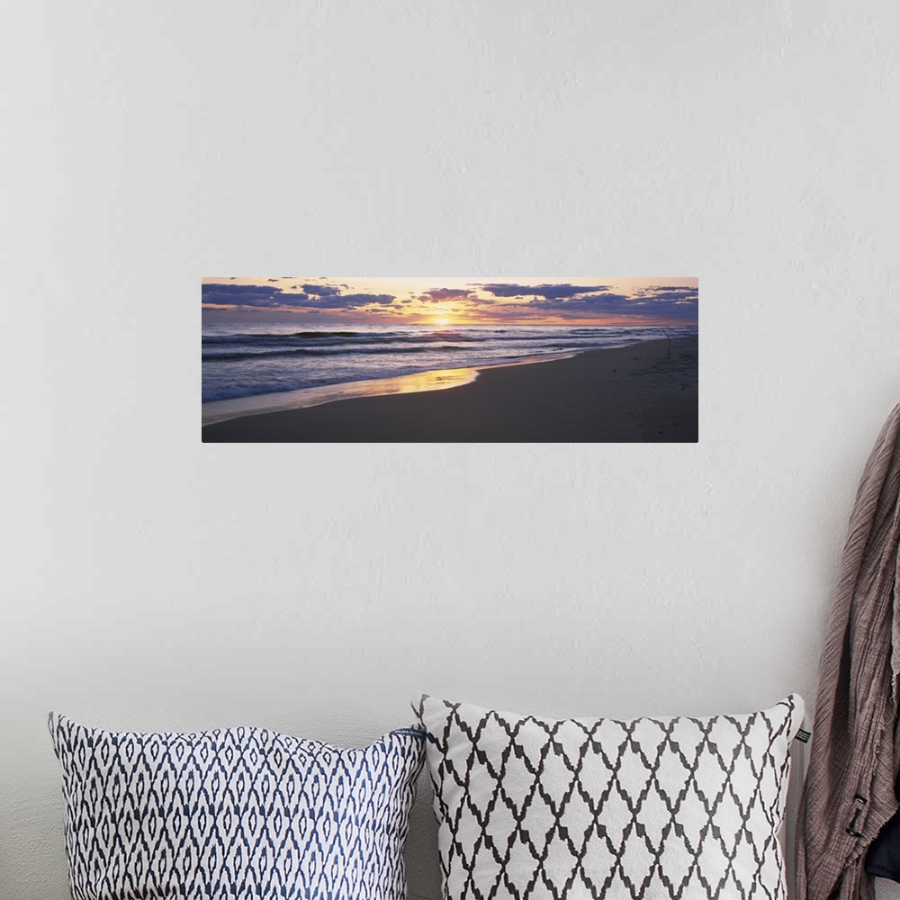 A bohemian room featuring The sand and ocean are pictured in wide angle view with the sunset off in the distance.