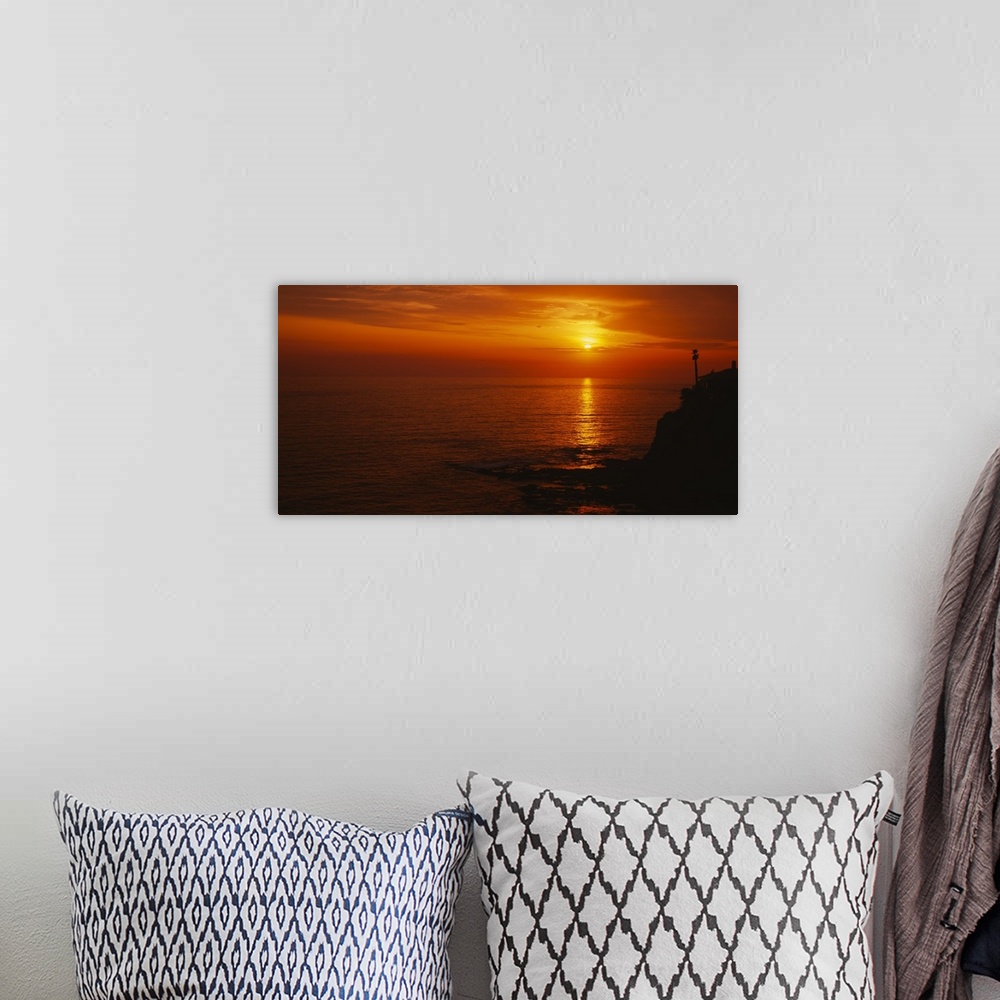 A bohemian room featuring Landscape, large wide angle photograph of a fiery sunset over calm waters at Laguna Beach in Cali...
