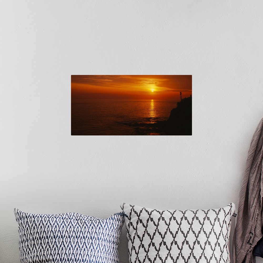 A bohemian room featuring Landscape, large wide angle photograph of a fiery sunset over calm waters at Laguna Beach in Cali...