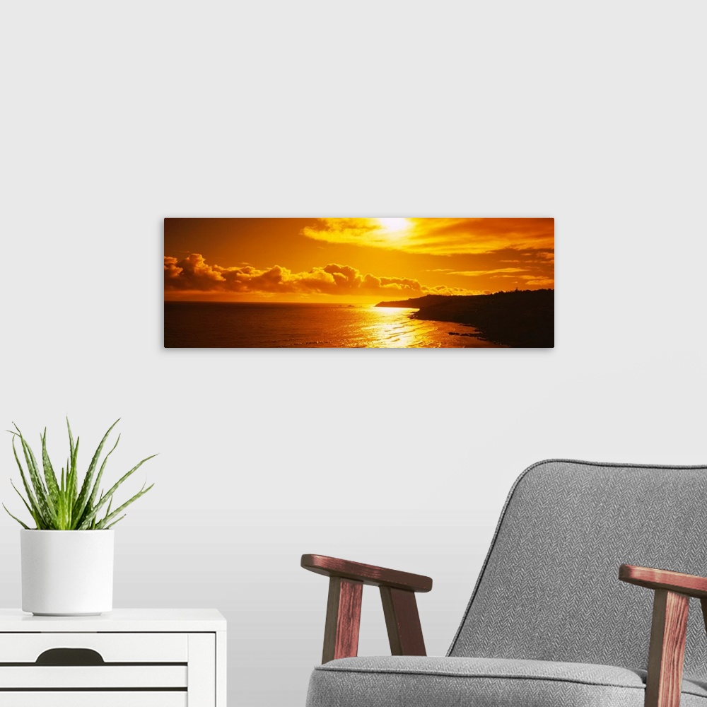 A modern room featuring This photograph is a panoramic seascape of the sun reflecting off the shallow beach water as it s...
