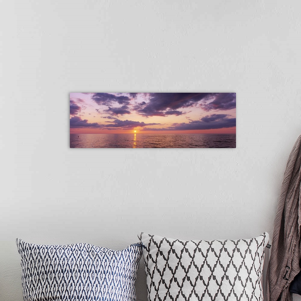 A bohemian room featuring Panoramic photograph taken of a sun setting over the Gulf of Mexico with warm colors throughout t...