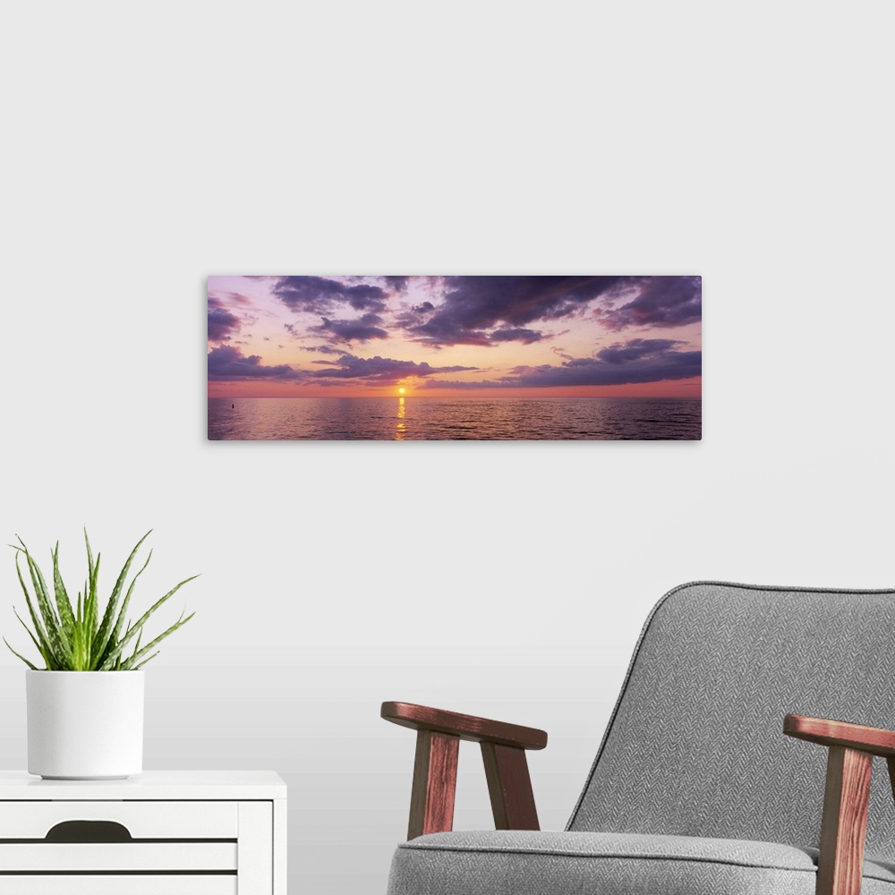 A modern room featuring Panoramic photograph taken of a sun setting over the Gulf of Mexico with warm colors throughout t...