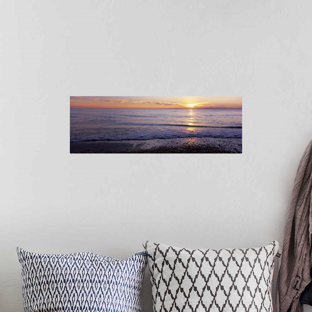 A bohemian room featuring This is a panoramic landscape photograph of waves softly washing up on the shore of a sandy beach.