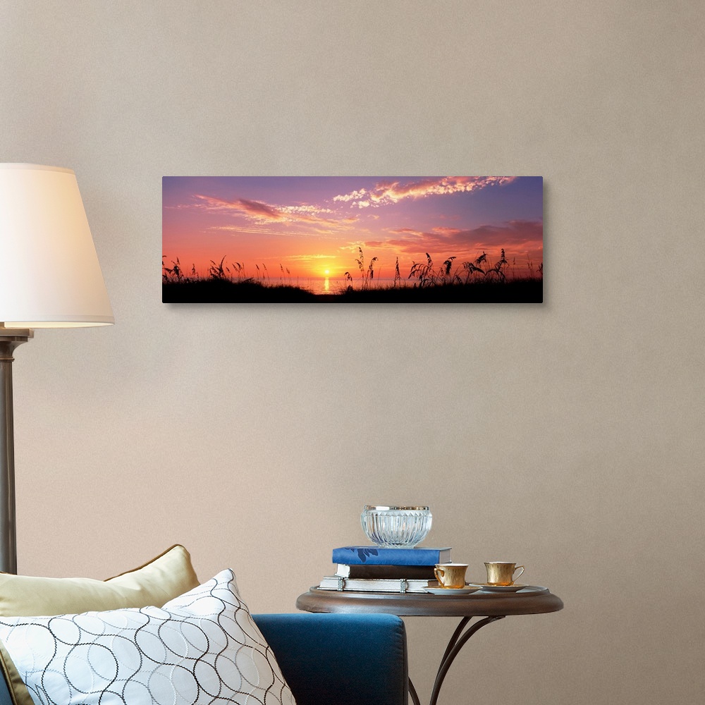 A traditional room featuring This wall art is a panoramic photograph of silhouetted sea grass in front of a calm sea at the en...