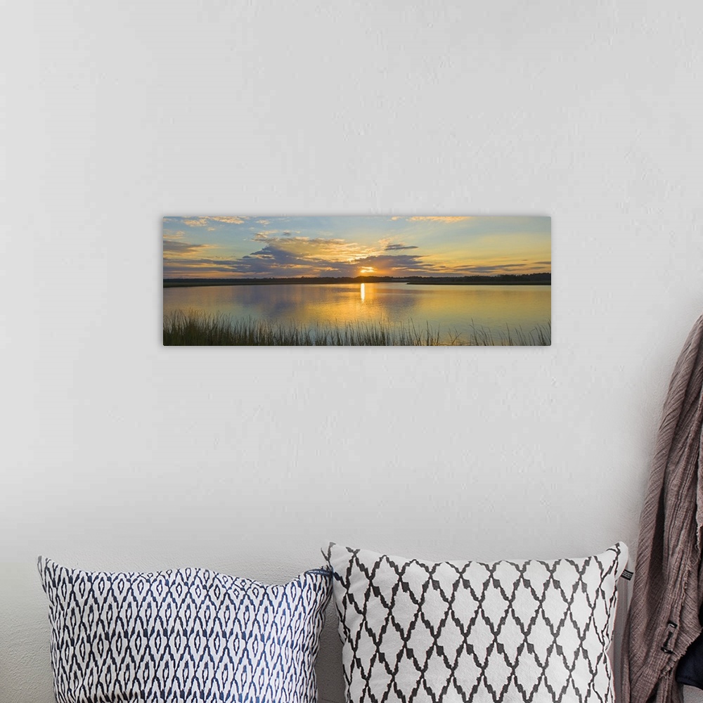 A bohemian room featuring Tall grass lines the bottom of this picture with a wide angle view of a body of water as the sun ...