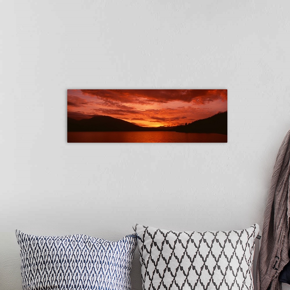 A bohemian room featuring Panoramic photograph of a vibrant fiery sunset over a silhouetted mountain landscape and Whiskeyt...