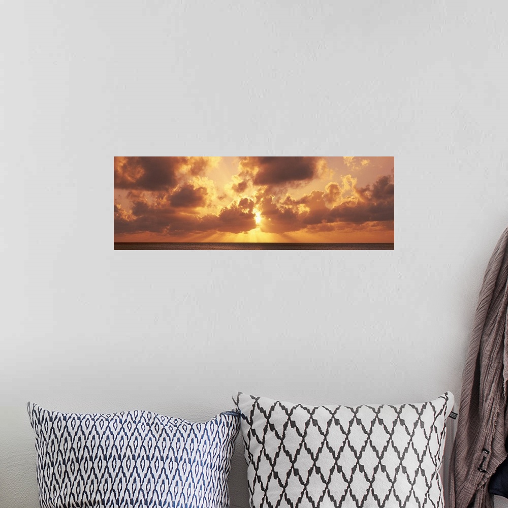 A bohemian room featuring Large panoramic photograph taken of a sunset behind the clouds with its rays bursting through and...