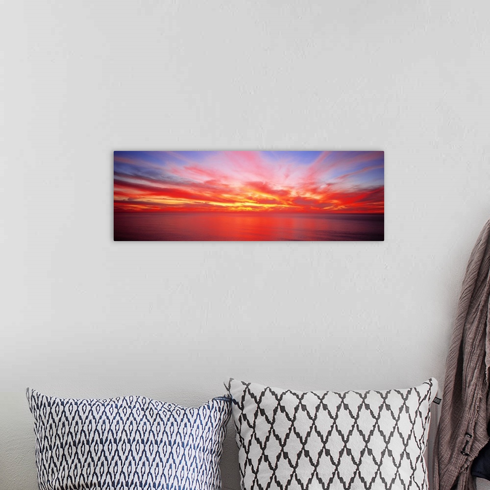 A bohemian room featuring Wide angle photograph on a giant wall hanging of the sky full of streaking clouds during a vibran...