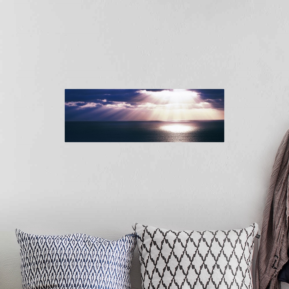 A bohemian room featuring Panoramic canvas photo of a sunset over the Pacific Ocean with no land in sight.