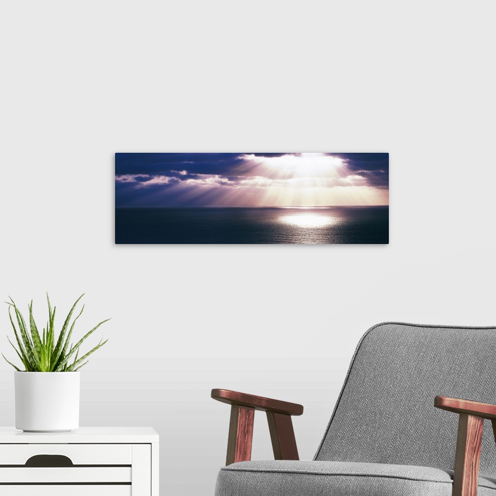 A modern room featuring Panoramic canvas photo of a sunset over the Pacific Ocean with no land in sight.
