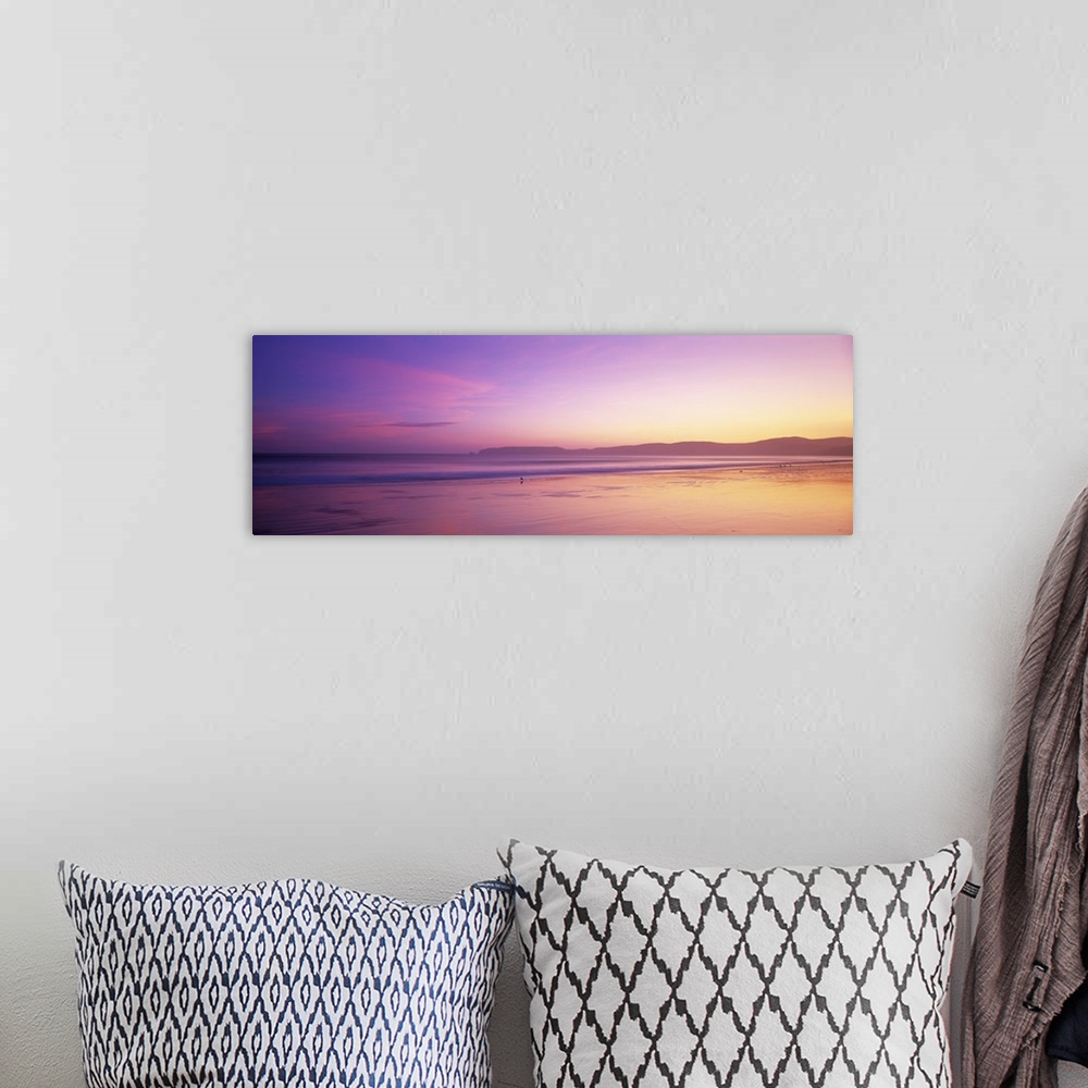 A bohemian room featuring This large panoramic piece shows a sun setting behind vast hills over the Pacific ocean.