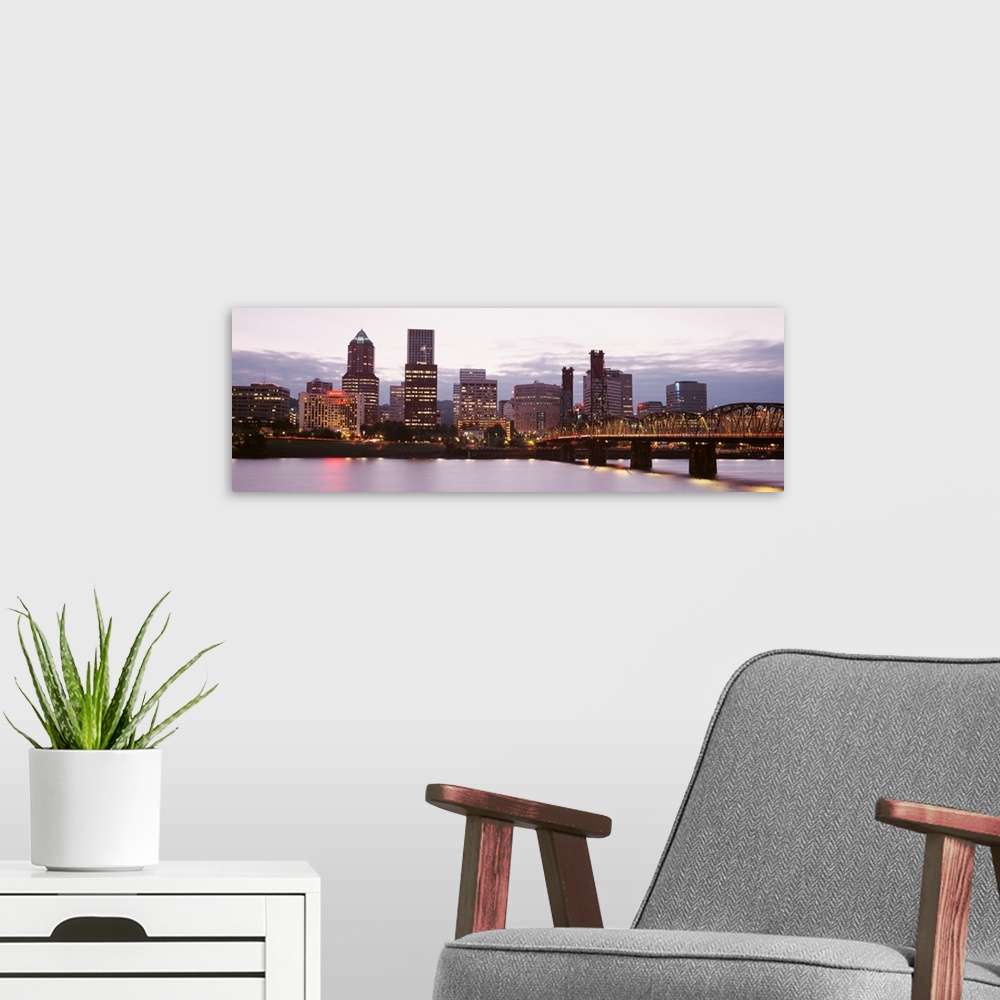 A modern room featuring Wide angle photograph of the Portland, Oregon skyline, lit up as the sun is setting.