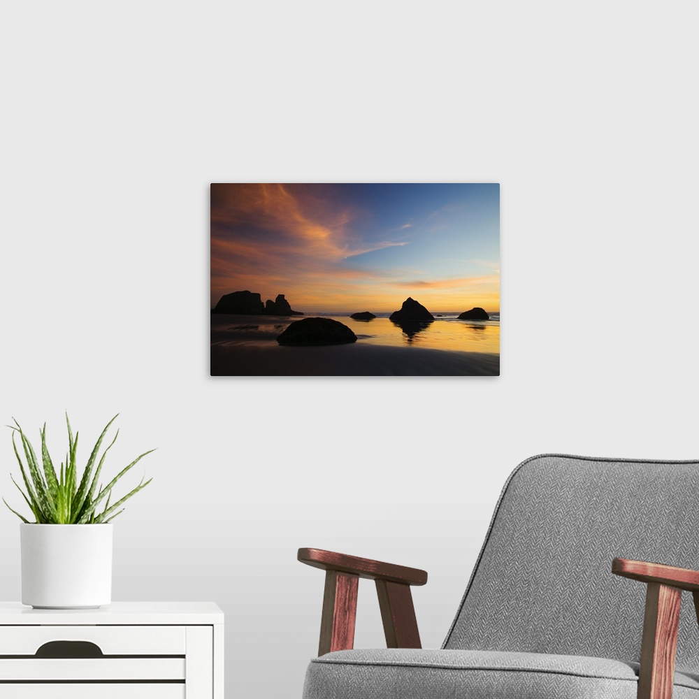 A modern room featuring Photograph of rocky shore at dusk.  There are huge rocks emerging from the sand and ripples of wa...