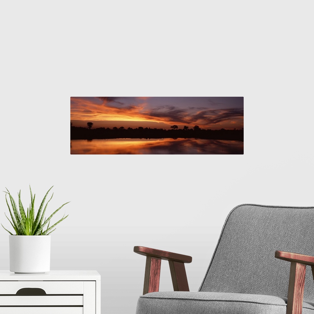 A modern room featuring Panoramic photo on canvas of a bright sunset along a river in Africa with a tree line silhouetted...
