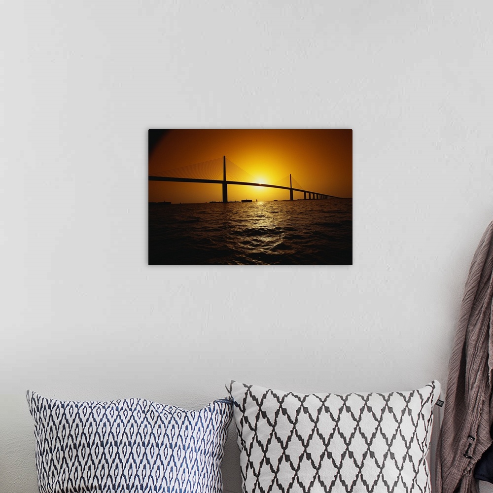 A bohemian room featuring Setting sun framed by the two towers of the Sunshine Skyway bridge, a concrete cable-stayed struc...