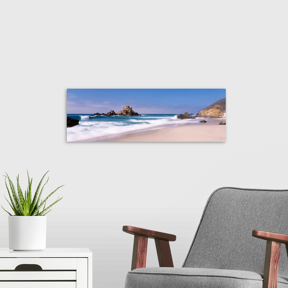 A modern room featuring Panoramic photographs displays the Pacific Ocean crashing into the sandy shores of this beach.  L...