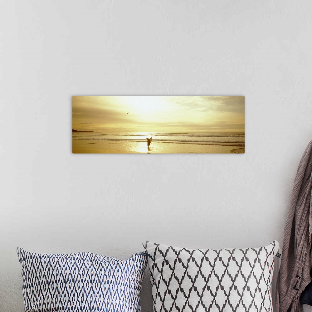 A bohemian room featuring This large panoramic piece is of a lone surfer walking on the beach as the sun is setting giving ...
