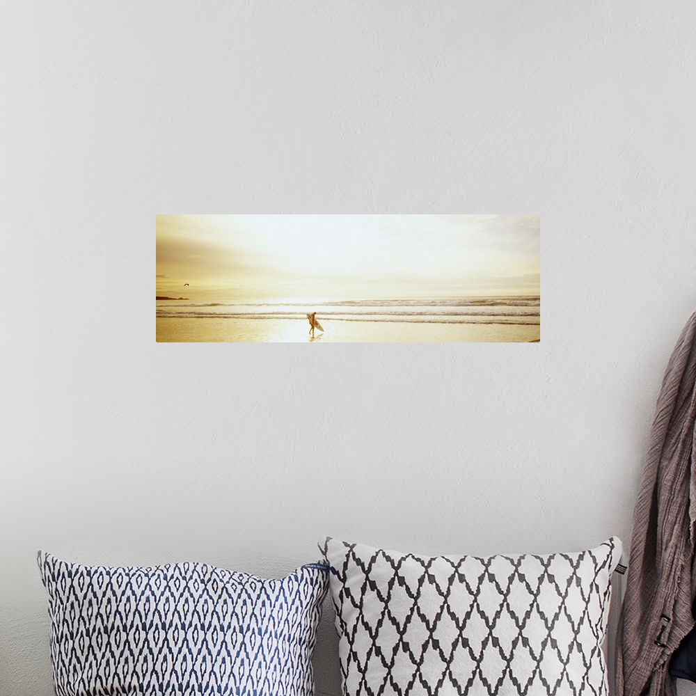 A bohemian room featuring Wide angle photograph of a lone surfer carrying a surf board along Ocean Beach as the tide rolls ...