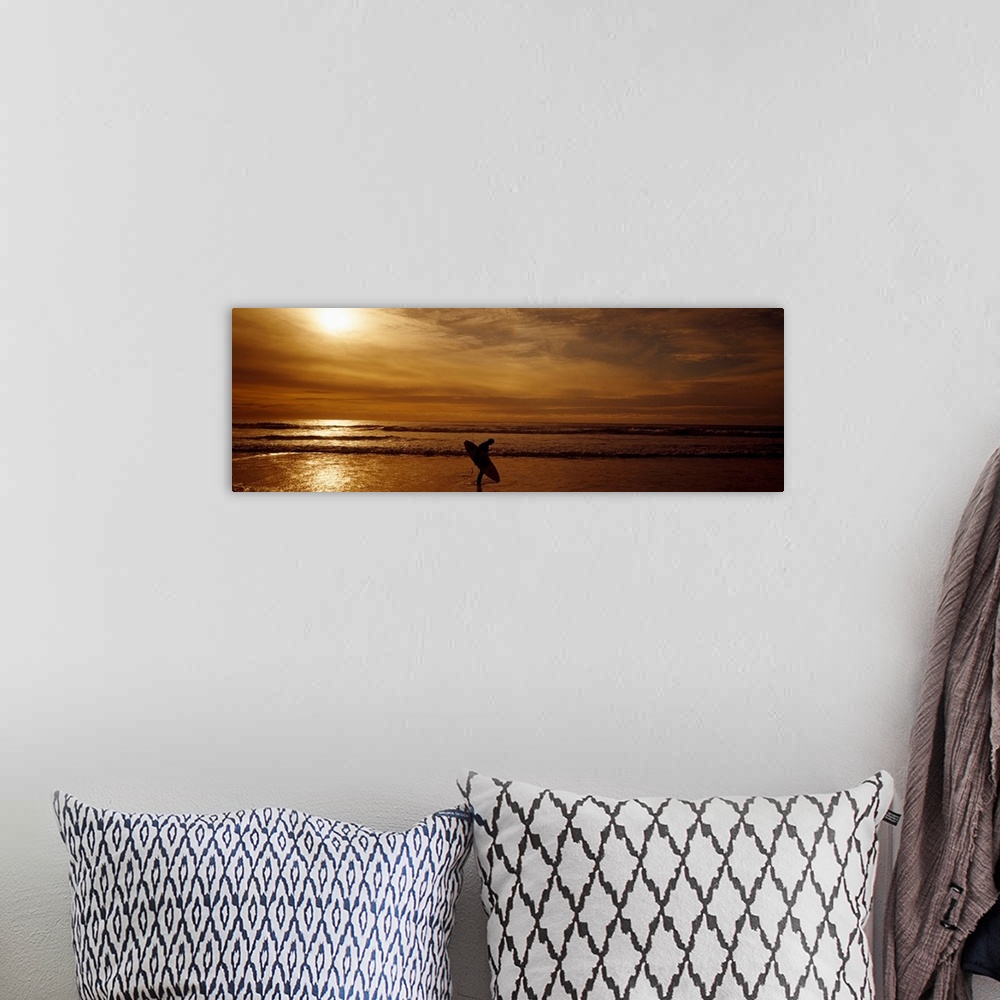A bohemian room featuring This horizontal panoramic photograph shows a lone figure emerging from the surf as the sun sinks ...