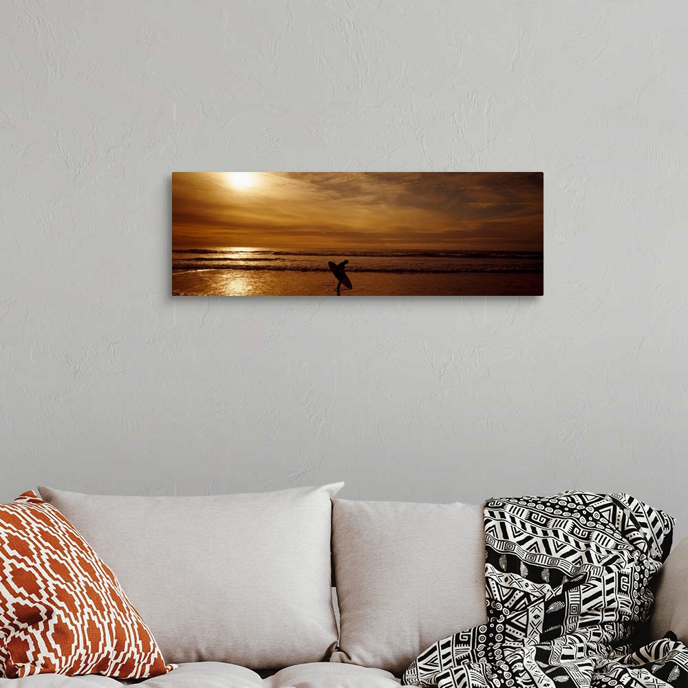 A bohemian room featuring This horizontal panoramic photograph shows a lone figure emerging from the surf as the sun sinks ...