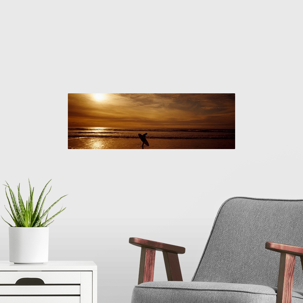 A modern room featuring This horizontal panoramic photograph shows a lone figure emerging from the surf as the sun sinks ...