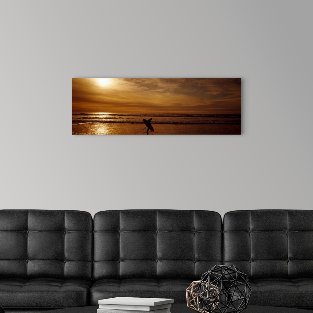 A modern room featuring This horizontal panoramic photograph shows a lone figure emerging from the surf as the sun sinks ...