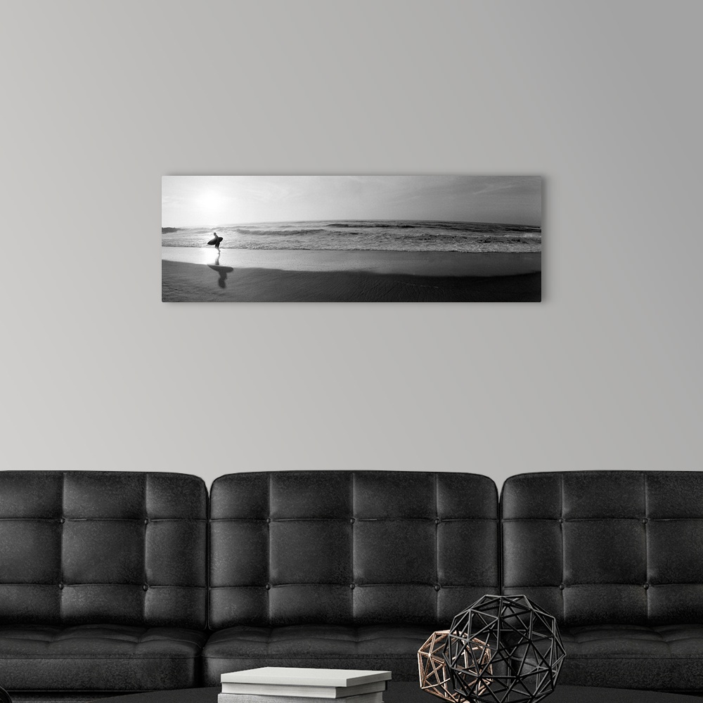 A modern room featuring Panoramic photograph of a surfer walking along a sandy beach in San Diego, California.  The tide ...