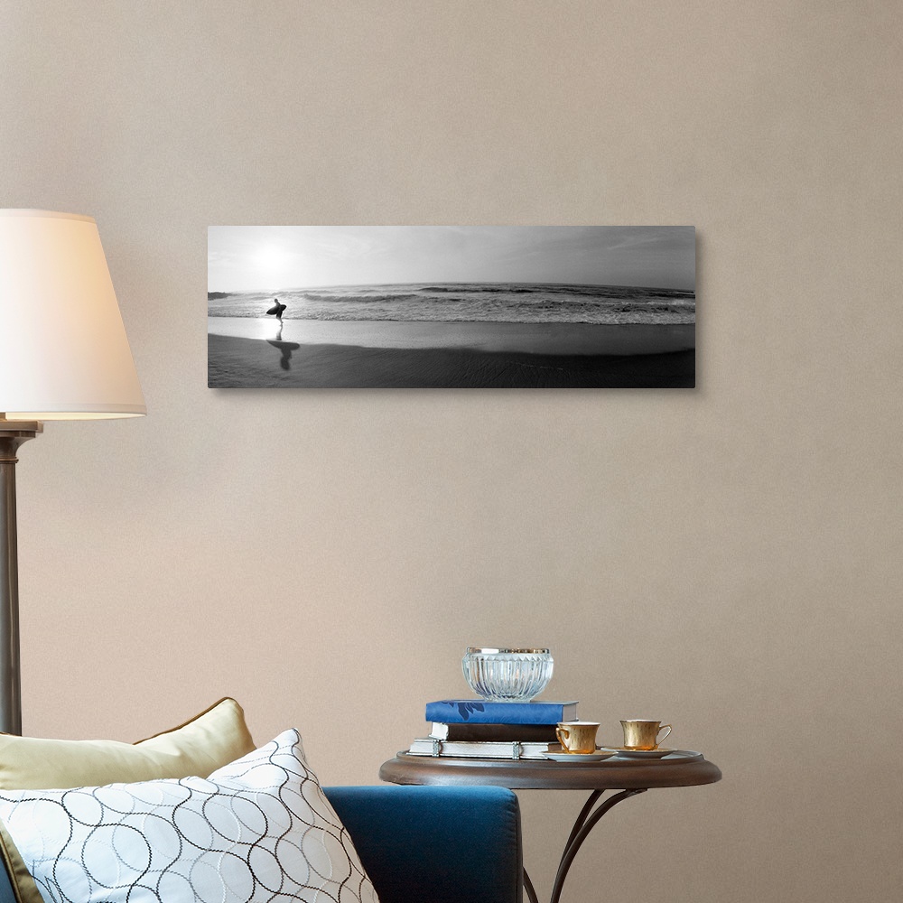 A traditional room featuring Panoramic photograph of a surfer walking along a sandy beach in San Diego, California.  The tide ...